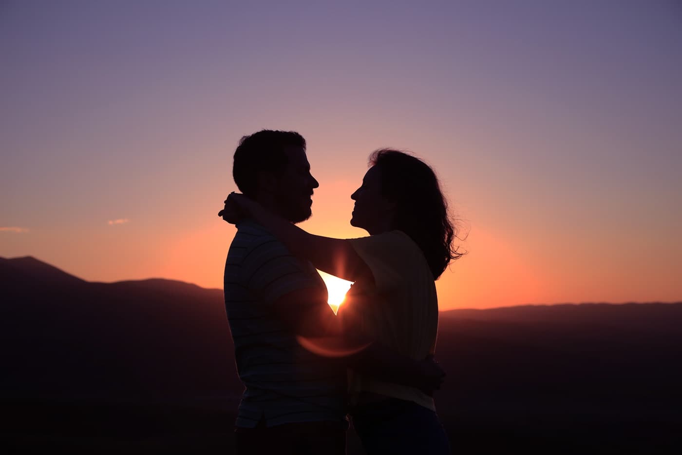 Two people sitting close together in silhouette